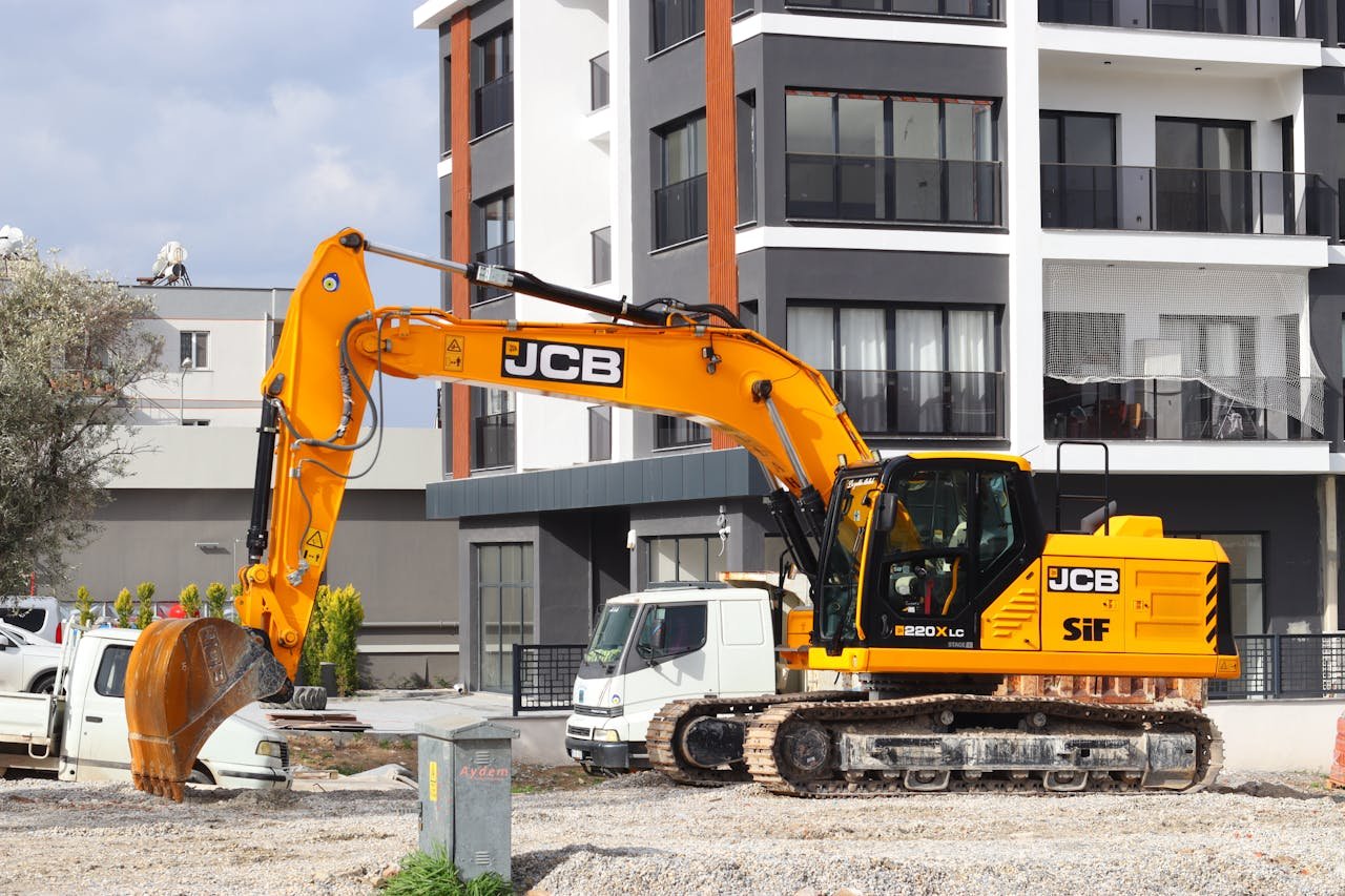 Mastering the First Impression: Your intriguing post title goes here A yellow excavator operating at a city construction site in front of modern buildings.